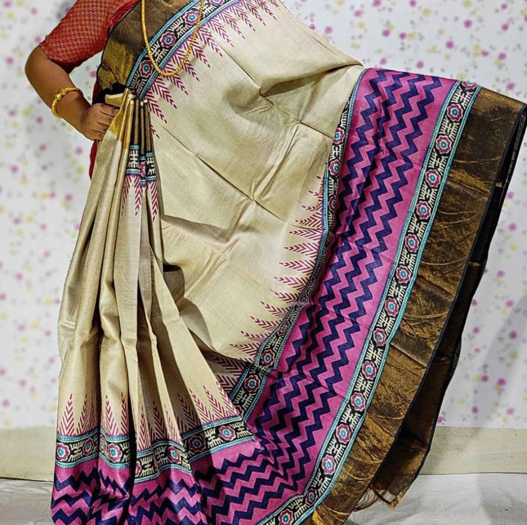A woman showcasing a Handloom Bhagalpuri Tussar Saree with a geometric panel design, featuring gold borders and a beige color with purple and black details.
