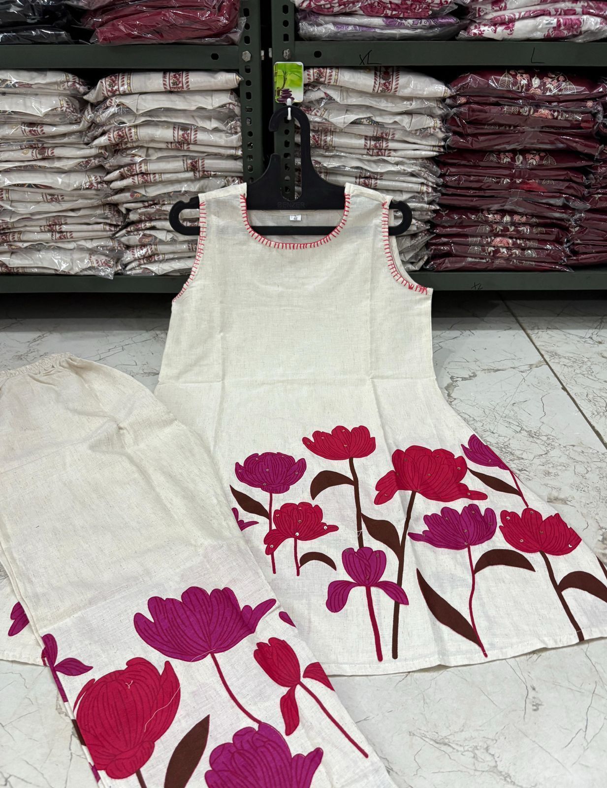 White sleeveless top with pink floral patterns on a white floor.