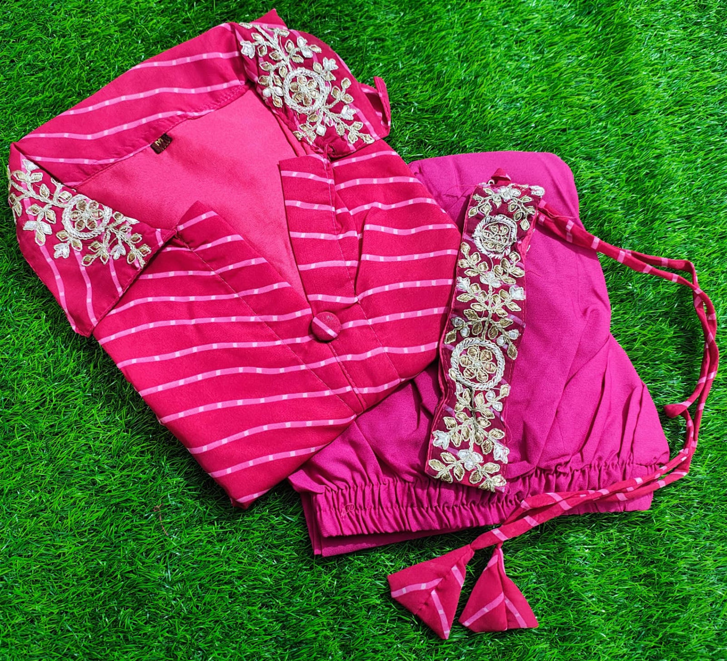 Pink saree with white embroidery on a green grass background