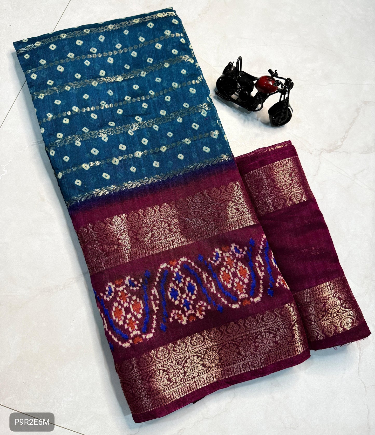 Blue and maroon saree with intricate patterns on a white background