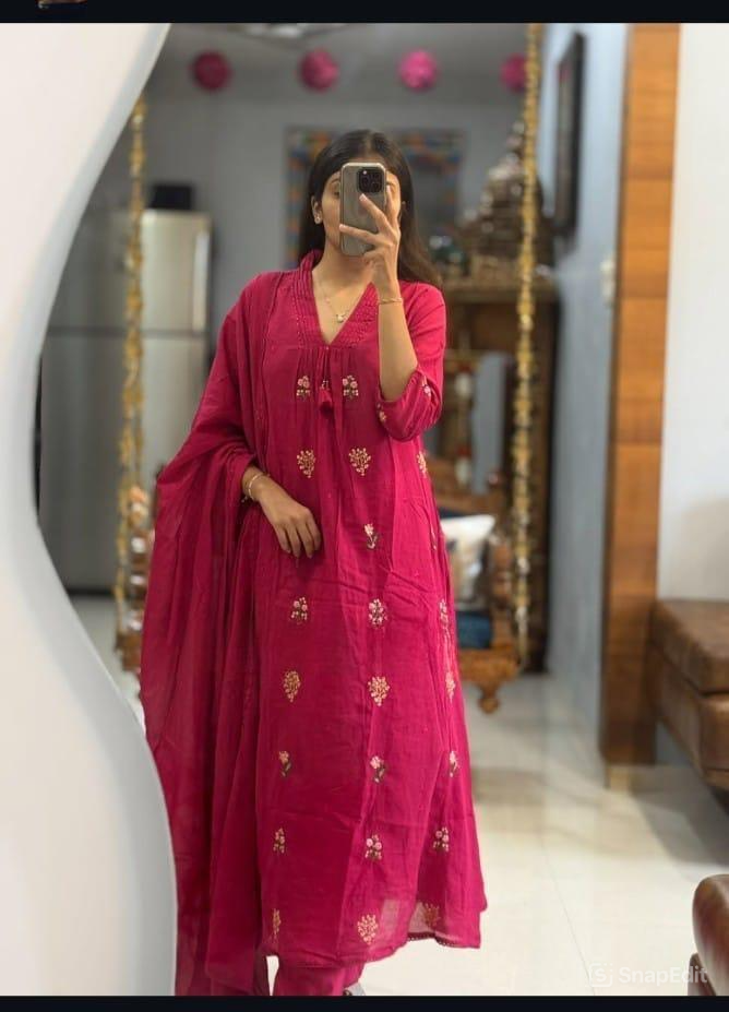 Person wearing a pink traditional outfit with floral patterns in a room.