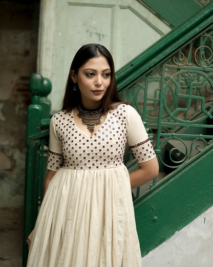 Woman in a white dress with brown polka dots standing on a green staircase.