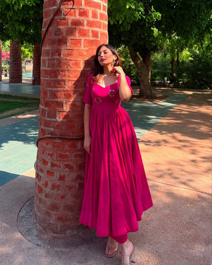 Woman in a pink dress standing next to a brick column outdoors