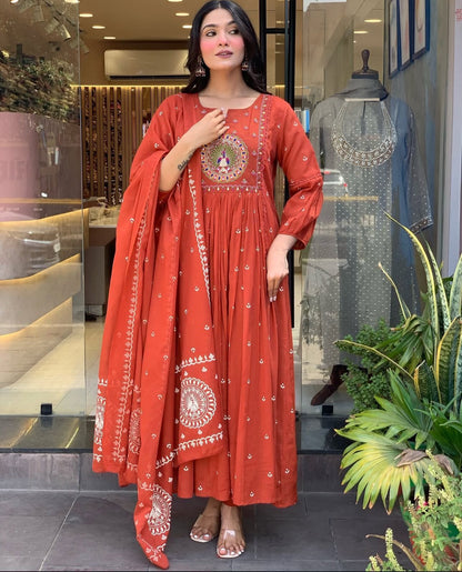 Woman wearing a red traditional outfit with white patterns in an indoor setting.