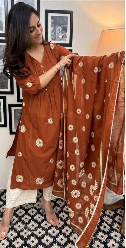 Woman holding a brown floral-patterned scarf in a room with framed pictures on the wall.