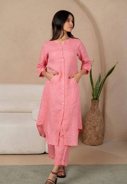 Woman wearing a pink kurta with pants standing in a minimalistic room.