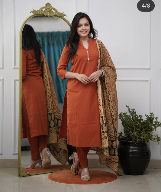 Woman in an orange kurta with a patterned dupatta standing in front of a mirror.