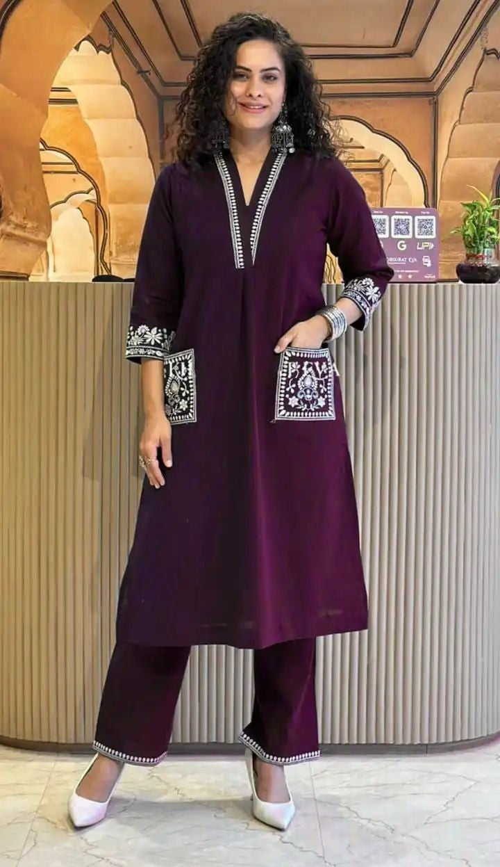 Woman wearing a purple traditional outfit with intricate designs in an indoor setting.