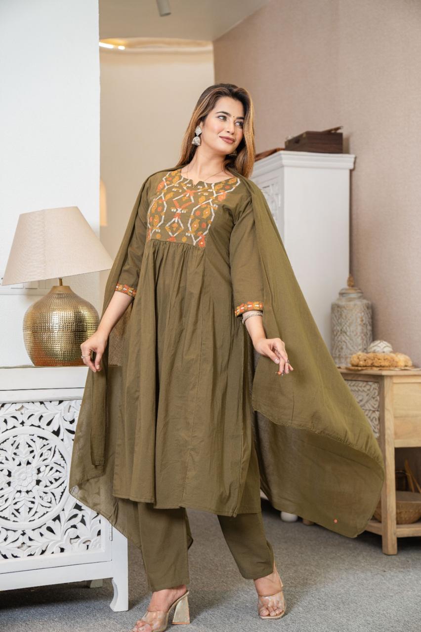 Woman wearing a green traditional outfit with embroidery in a home setting