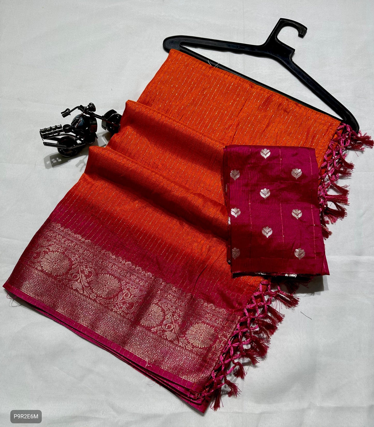 Red and orange saree with a pink border on a white background