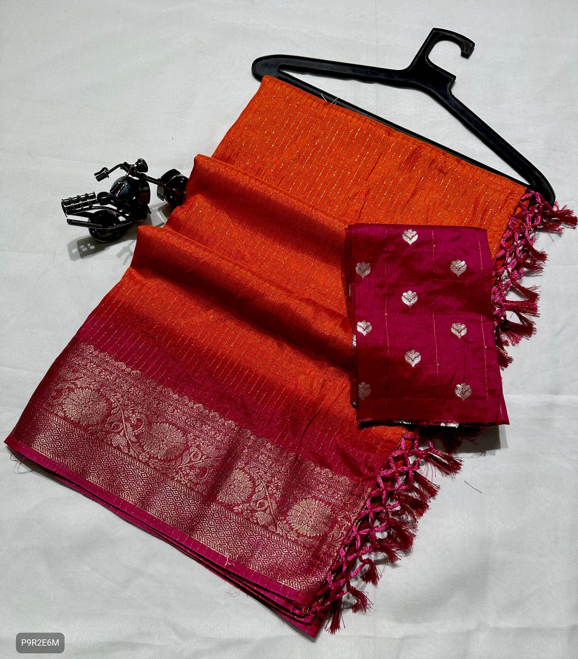 Red and orange saree with a pink border on a white background