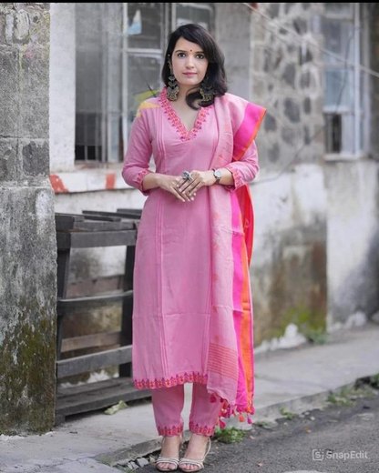 Woman in a pink traditional outfit standing against a stone wall.