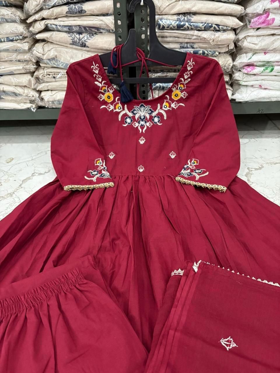 Red embroidered dress on a hanger with a warehouse background