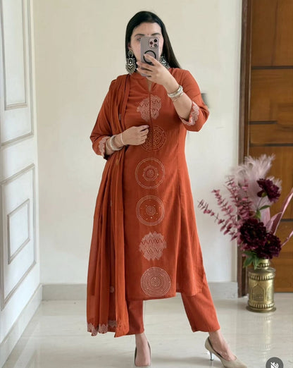 Woman taking a mirror selfie wearing an orange kurta with white patterns in a well-lit room.