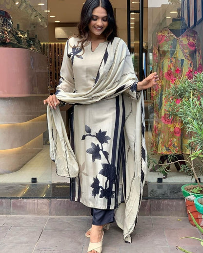 Woman in a floral outfit standing in front of a store with mannequins and plants.