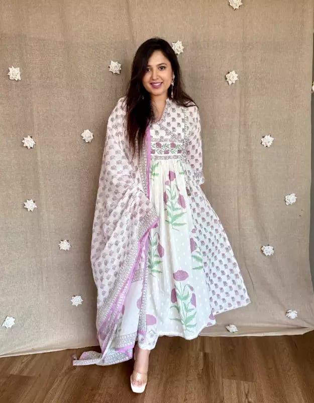 Woman wearing a white and green traditional outfit with a beige background